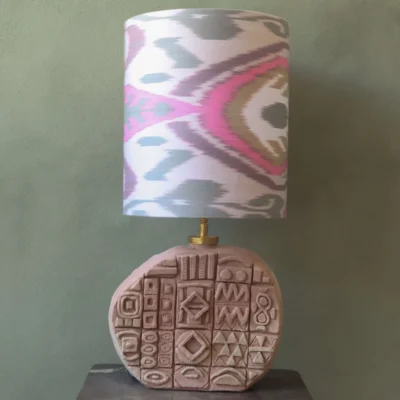lamp base in terra with patterns on it in small tiles. african symbols. Lampshade in Ikat pink.